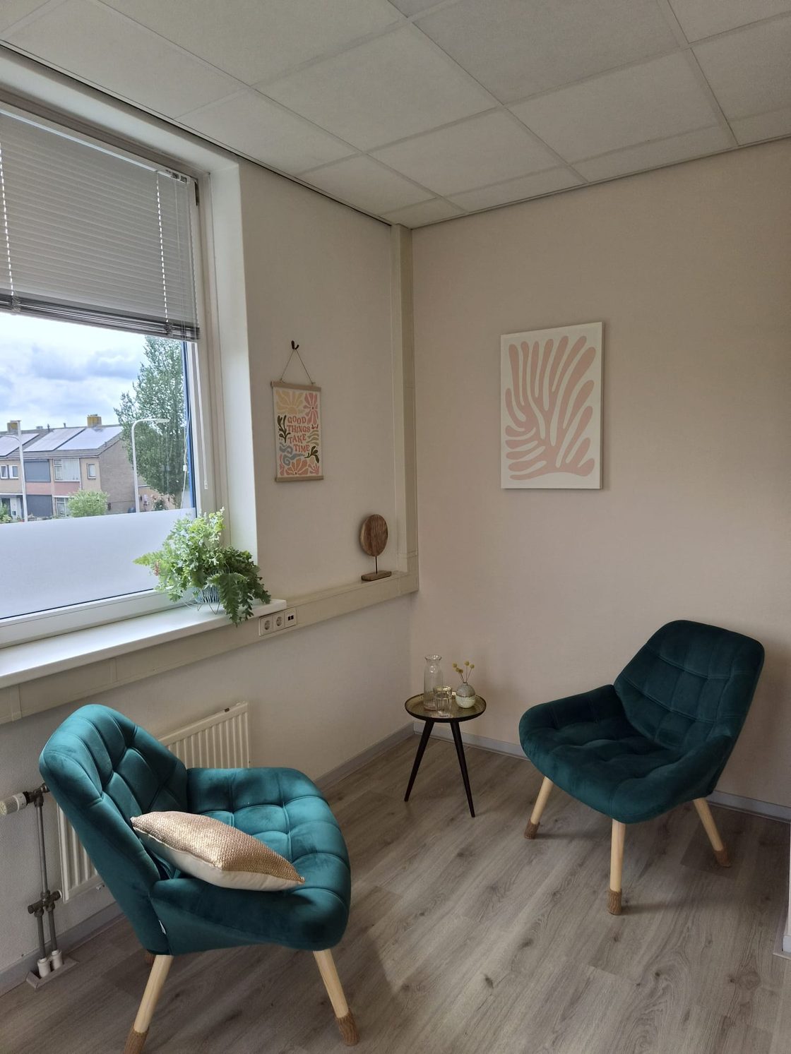 De praktijkruimte: twee fauteuils bij het raam, met een bijzettafel ertussen